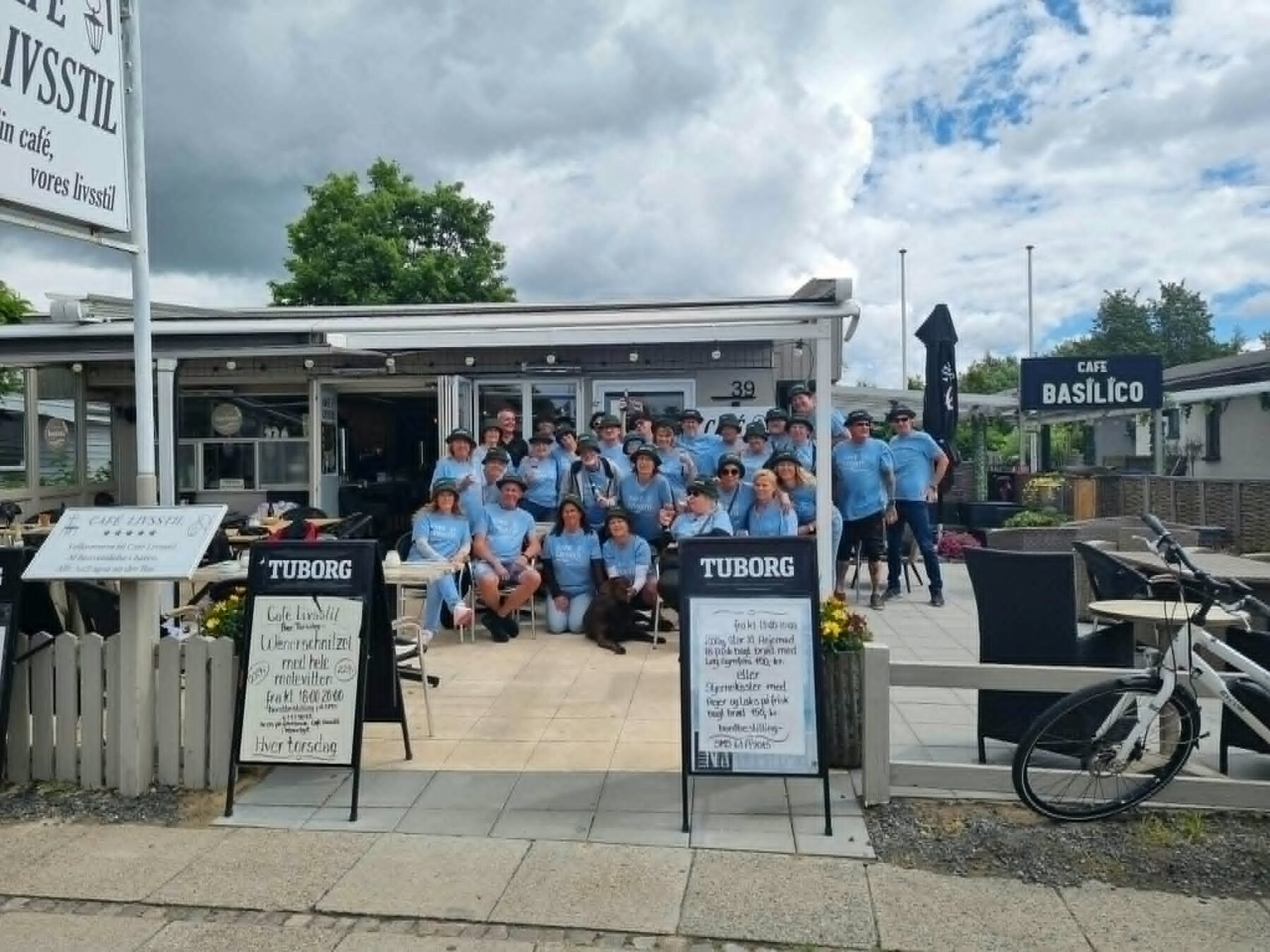 Deltagerne i Tour de Marielyst samlet foran Café Livsstil i caféens lyseblå t-shirts