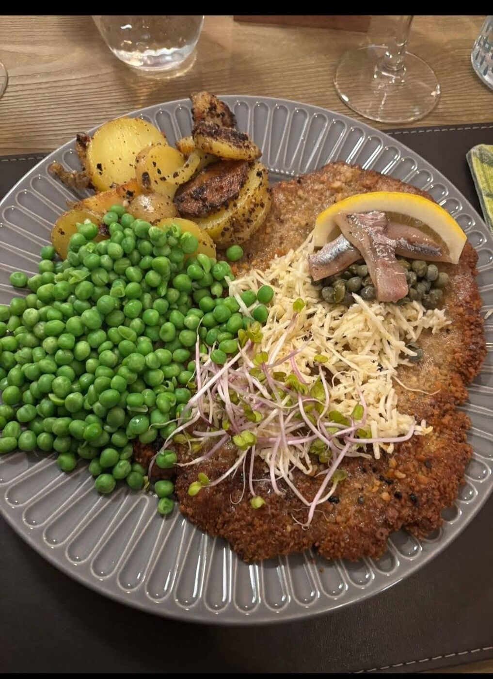 Pandestegt wienerschnitzel med ærter, brasede kartofler, revet peberrod, ansjoser og kapers