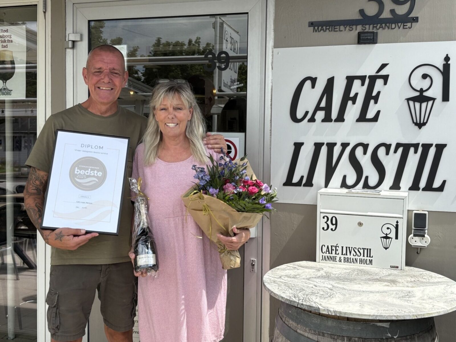 Jannie og Brian Holm foran Café Livsstil med diplomet for bedste service